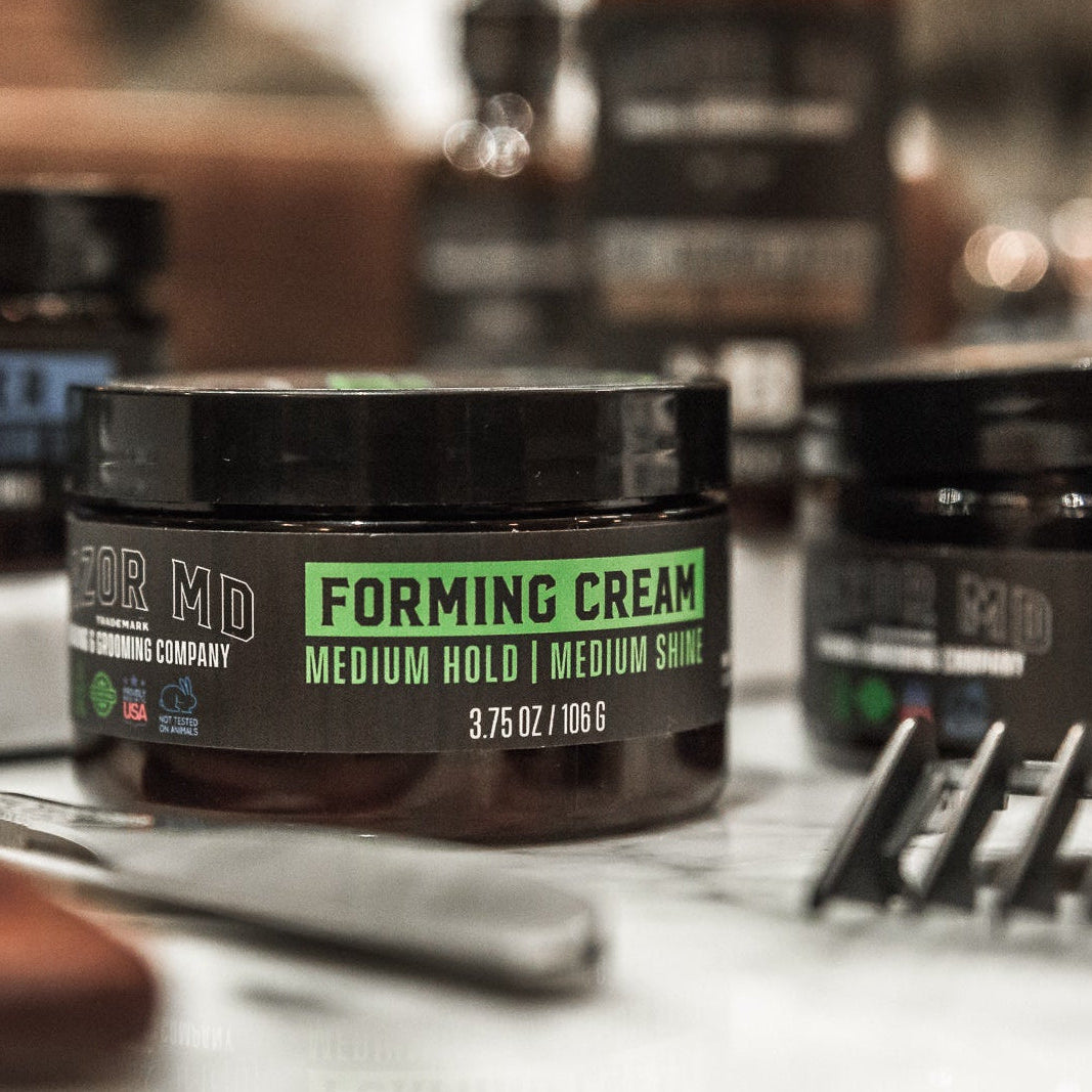 Barber shop products including a jar of RAZOR MD forming cream and pomade on a counter.